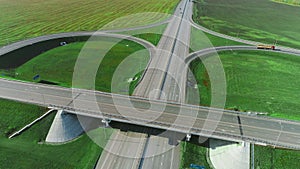 The drone moves over a traffic intersection. Trucks and cars drive along the highway. The road on a sunny day. Autobahn