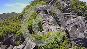 Drone Moves to Island Mountain and Girl Shows Likeness on Rocks