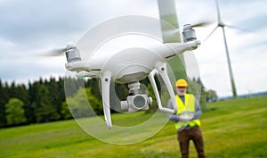 Drone operated by construction worker inspecting wind turbine