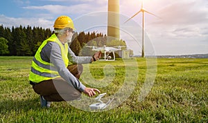 Drone operated by construction worker inspecting wind turbine