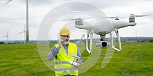 Drone operated by construction worker inspecting wind turbine