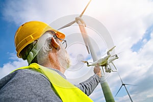 Drone operated by construction worker inspecting wind turbine