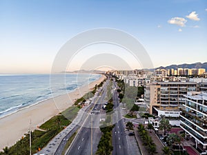 Drone photo of sunrise in Barra da Tijuca beach and boardwalk, beachfront buildings catching the early light, Rio de