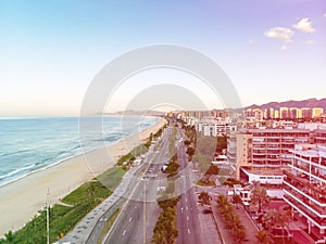 Drone photo of sunrise in Barra da Tijuca beach and boardwalk, beachfront buildings catching the early light, Rio de