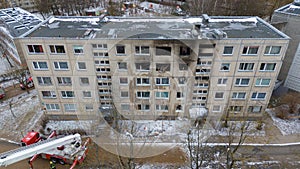 Drone photography of aftermath multistory residential building fire and emergency service cleaning up during winter day