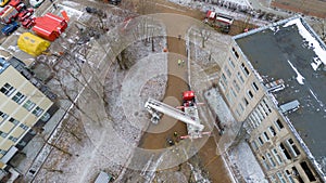 Drone photography of aftermath multistory residential building fire and emergency service cleaning up during winter day