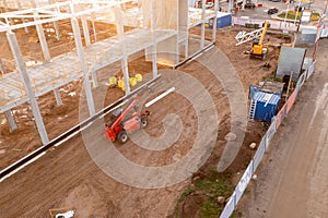 Drone photography of constructions site of large commercial building with construction machinery and construction workers during