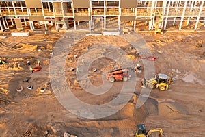 Drone photography of constructions site of large commercial building with construction machinery and construction workers during