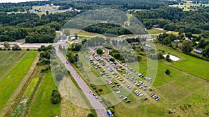 Drone photography of a music festival car park, main entrance and festival in background surrounded by forest during summer day photo