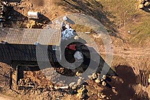 Drone photography of tractor taking hay bales to the shed with farm animals