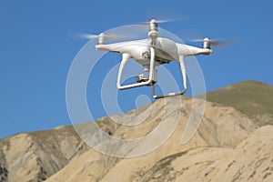 Drone quad copter with high resolution digital camera on the sky . White drone with digital camera flying in sky over mountain Dro