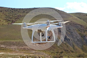 Drone quad copter with high resolution digital camera on the sky .White drone with digital camera flying in sky over mountain Dron