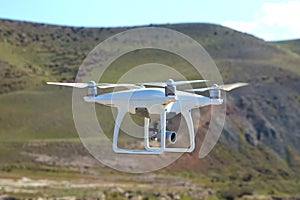 Drone quad copter with high resolution digital camera on the sky .White drone with digital camera flying in sky over mountain Dron