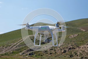 Drone quad copter with high resolution digital camera on the sky .White drone with digital camera flying in sky over mountain Dron