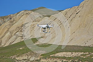 Drone quad copter with high resolution digital camera on the sky .White drone with digital camera flying in sky over mountain Dron