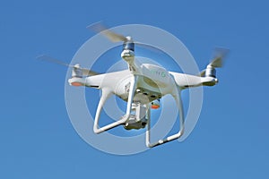 Drone quad copter with high resolution digital camera on the sky .White drone with digital camera flying in sky over mountain Dron