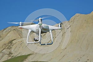 Drone quad copter with high resolution digital camera on the sky .White drone with digital camera flying in sky over mountain Dron