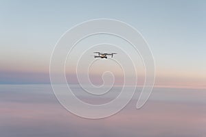 Drone quadcopter with digital camera above sunset sky and Earth Surface. Concept