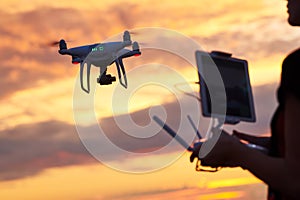 Drone quadcopter with digital camera flying at sunset