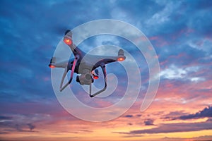 Drone quadcopter with digital camera flying at sunset