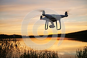 Drone quadcopter with digital camera flying at sunset