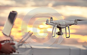 Drone quadcopter with digital camera flying at sunset