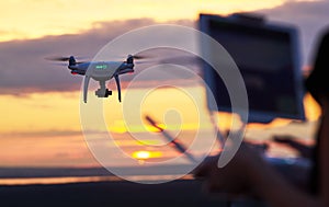 Drone quadcopter with digital camera flying at sunset