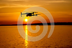 drone quadcopter with digital camera flying at sunset. Beautiful sunset on the river