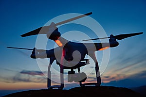 Drone quadrocopter with digital camera at sunset