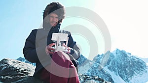 Drone remote controlling. Hand and remote view of a drone pilot operator. A traveler in the snowy mountains takes