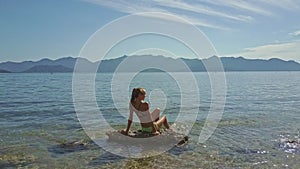 Drone Removes from Blond Girl in Ocean to Blue Sky