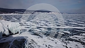 Drone rises above the frozen crystal ice of the lake Baikal. Top view. Natural background and patterns