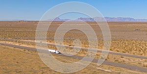 DRONE: Semi-trailer truck transports merchandise across Utah desert on sunny day