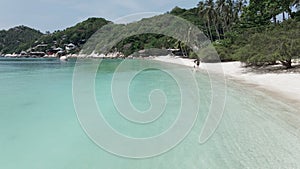 An drone shot of a beautiful beach where a happy romantic middle aged couple enjoying walk on the beach. Travel vacation