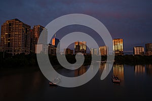 Drone shot of boats in the town lake with Austin architectures in the background at night