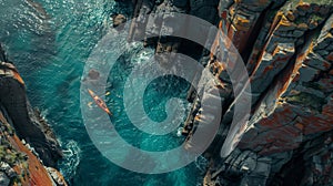 Drone shot capturing a solitary kayaker navigating waters where towering mountain cliffs plunge into the ocean