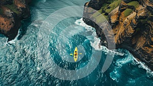 Drone shot capturing a solitary kayaker navigating waters where towering mountain cliffs plunge into the ocean