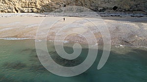 Drone shot of cliffs and rocks on an empty beach in Sesimbra, Portugal