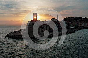 Drone shot of a coastal city's buildings line by the sea under cloudy sky at sunset