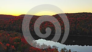 Drone shot coming down slowly at sunset behind the colorful trees in the park Mont-Loup-Garou