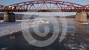 Drone Shot Flies Forward Over the Frozen River and Under the Red Steel Bridge, Aerial 4k Footage