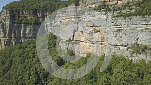 Drone shot flying close to a huge rock cliff. Aerial view on mountain landscape with cliffs. Steep cliff face and