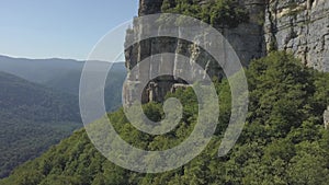 Drone shot flying close to a huge rock cliff. Aerial view on mountain landscape with cliffs. Steep cliff face and