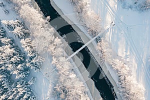 Drone shot frozing small river, suspension bridge