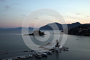 Drone shot of the Holy Monastery of Panagia Vlacherna and boats on a harbor in Corfu, Greece