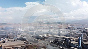 Drone shot of industrial zone with thick smog and burning fossil fuels. Zoom in aerial shot of factory zone shot from