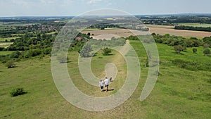 Drone shot of mature couple walking with pet dog through beautiful English Countryside