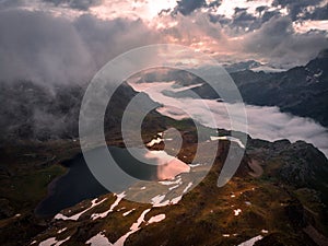 Drone shot of a mountain lake with fog and stormy clouds at sunset