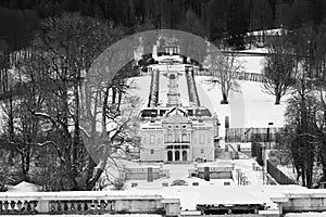 Drone shot over Linderhof Palace in Ettal, Germany with snowy trees, grayscale shot photo