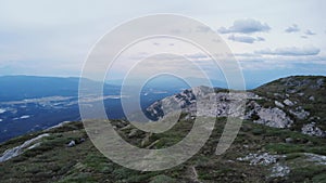 Drone shot over mountains towards Whitehorse cloudy sky and blue mountains background